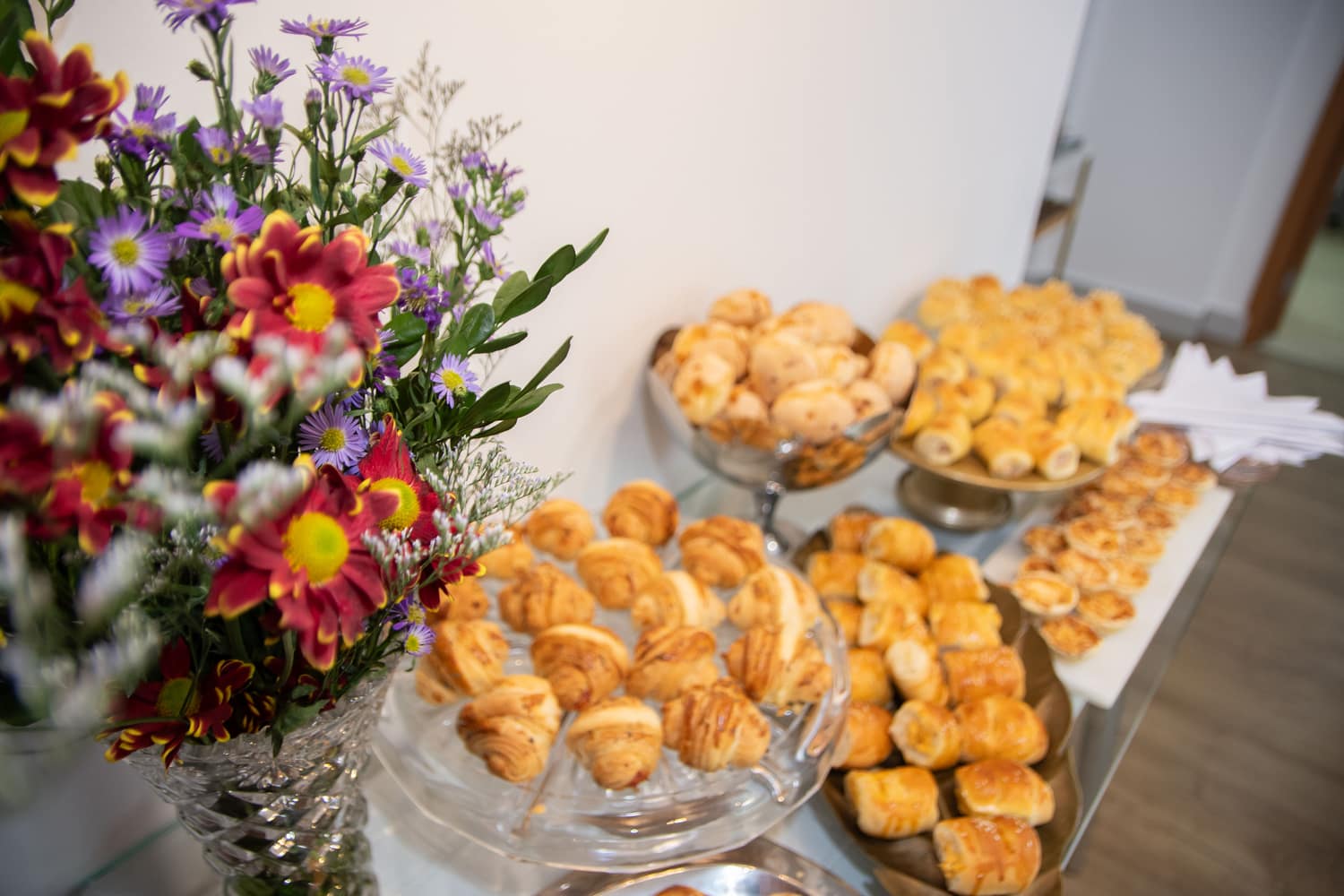 Mesa de inauguração com flores e salgados na Clínica Aragão & Cesar